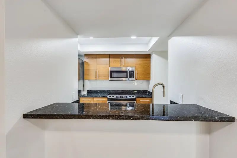 Kitchen pass-through with a dark granite breakfast counter seen from the living area