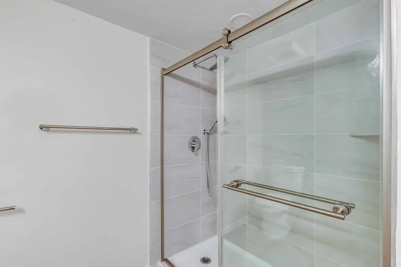 Tiled shower with a sliding glass door and brushed nickel fixtures