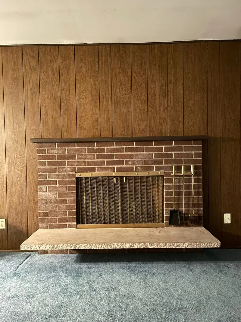 Brick fireplace with a raised hearth set in a wood paneled wall