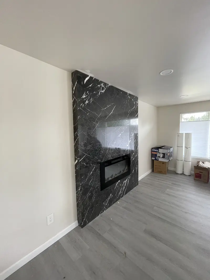 Floor to ceiling black marble slab fireplace wall with a linear fireplace