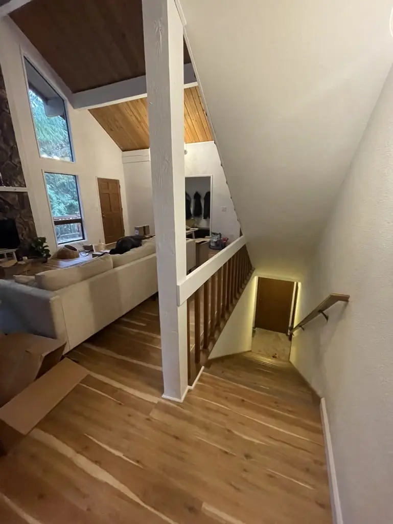 Stair landing with a new wood floor, a railing and a tall window under a wood ceiling