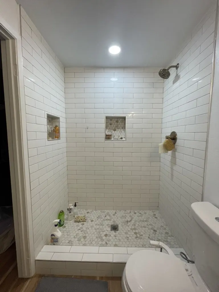 Walk-in shower with white subway tile, two niches and a pebble floor