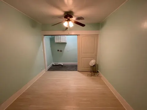 Remodeled laundry room area in Seattle, WA with sage green walls, new flooring, a ceiling fan and a sliding door