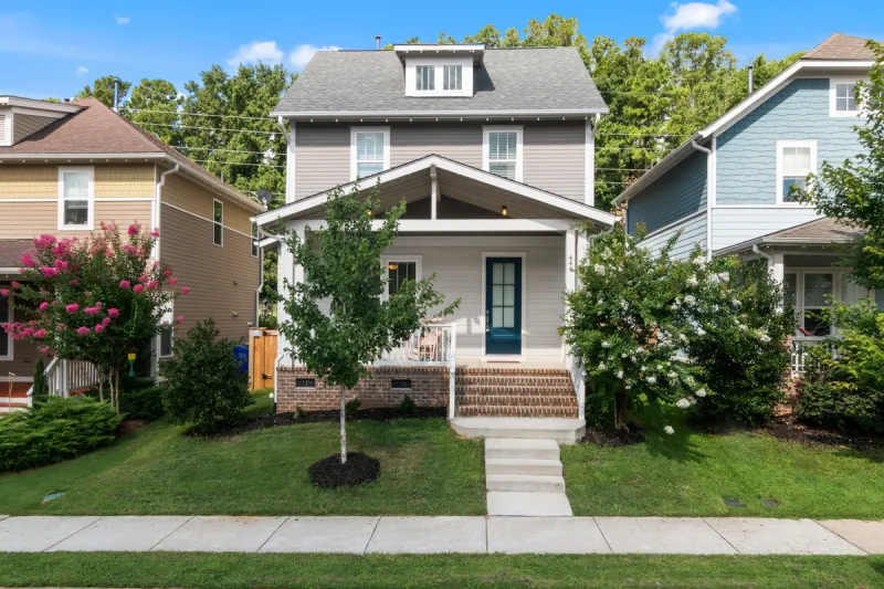Two story craftsman style house with gray siding, white double hung windows and a covered front porch