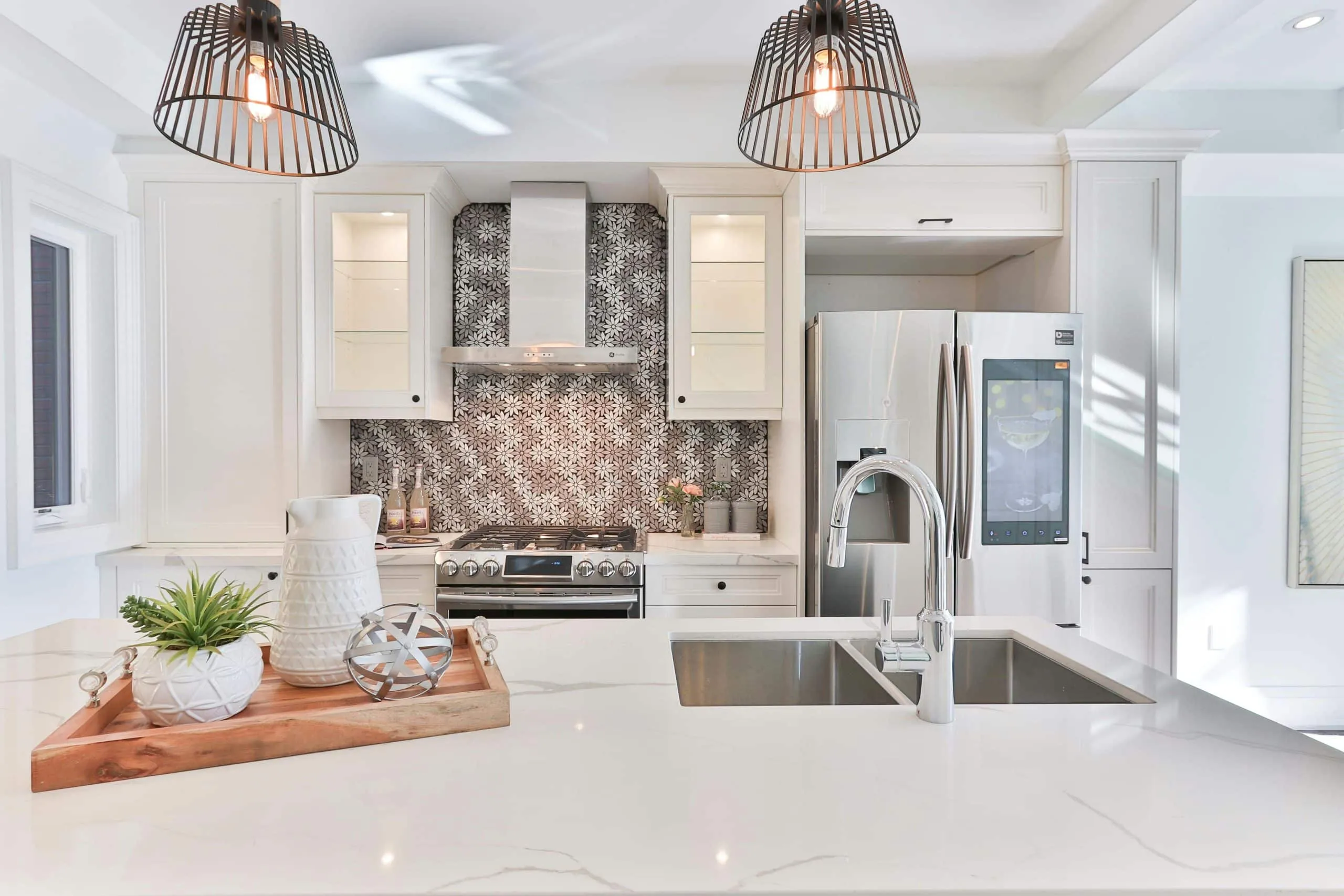 White kitchen with woven pendant lights over a counter and a patterned backsplash