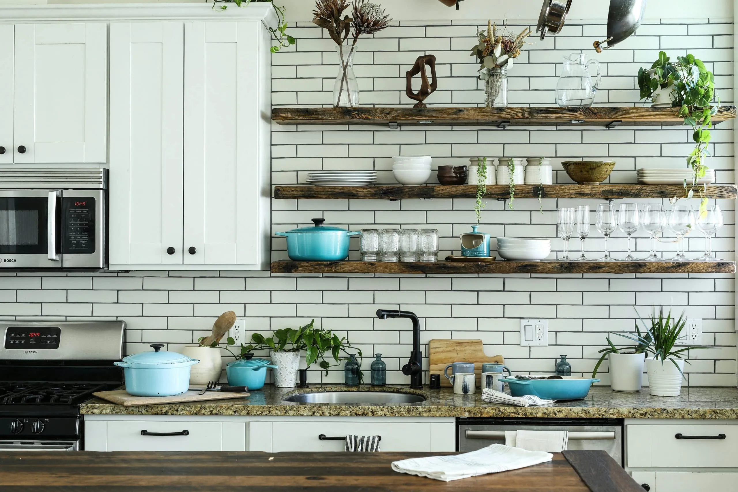Kitchen with white subway tile, open wood shelves and white cabinets
