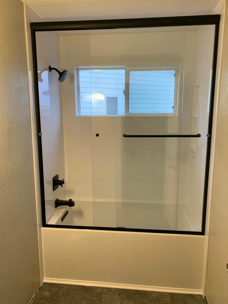 a bathroom with a glass shower door and tile floor